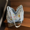 Sac fourre-tout en jean bleu clair avec broderie colorée et bords effilochés sur escalier - Bleu Denim