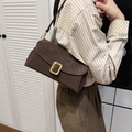 Sac bandoulière en daim marron avec boucle dorée porté par un mannequin au style épuré - Marron