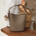 Brown litchi leather bucket bag with cute bear charm on a rustic wooden tabletop - With Pendant / Elephant Gray