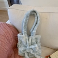 Close-up of light blue plush handbag with a cute bow detail on a soft sofa - Light Gray