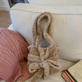 Brown plush handbag with large bow detail displayed on white fabric and vintage books - Light Coffee