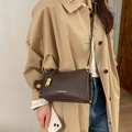 Détail du sac bandoulière marron foncé à texture litchi avec boucle dorée et pompon doux - Avec Pendentif / Marron