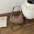 Detailed close-up of dark brown lychee leather crescent bag with silver twist lock on wood - Brown