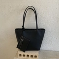 Detail of black pebbled leather tote with white contrast stitching and a small pouch - Black