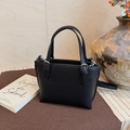Detail shot of black pebble leather bucket bag with silver hardware on a wooden background - Black