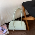 Close-up of light green bowling handbag with double handles and star pendant on wood floor - Green