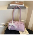 Detail view of lavender faux leather boston bag featuring white lace bows and gold logo - Purple