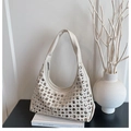 Nahaufnahme einer weißen Hobo-Tasche mit silbernen Metallnieten auf modernem Hintergrund - Weiß