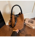 Detailaufnahme der braunen Wildleder-Beuteltasche mit schwarzem Ledergriff und Anhänger - Braun