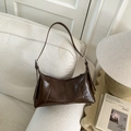 Close-up of retro dark brown hobo bag on white sofa with silver buckle detail - Brown