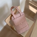 Detail of pink quilted nylon shoulder bag with front flap pocket on a wooden chair - Light Pink