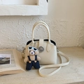 Detail of minimalist cream leather handbag with silver twist lock and cute bear charm - With Charm / White