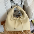 Beige faux leather croissant handbag with knot detail on a rustic woven chair - Yellow
