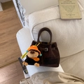 Detail der dunkelbraunen Wildleder-Beuteltasche mit Affen-Plüschtier auf einem Sofa - Kaffee (Mit Anhänger)