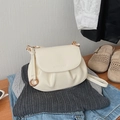 Detailed view of cream pleated crossbody bag with gold hardware and logo engraving - White