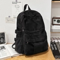 Zaino nero minimalista in tela con design multi-tasche su una scrivania vintage - Nero