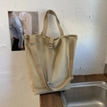 Detail of khaki canvas bucket bag with adjustable metal eyelet straps on wood - Khaki