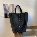 Détail d'un sac seau en toile noire avec œillets métalliques et bandoulière réglable - Noir