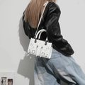 Close-up of white motorcycle-style mini bag with silver studs and tassel details - White