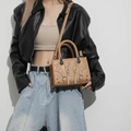 Detail of khaki leather handbag featuring silver rivets and woven handle textures - Khaki
