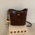 Brown bucket bag with dual-texture leather, gold clasp and horse charm detail - Brown