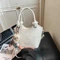 Chic cream white bucket bag with knotted handle and plush bear charm on a seat - White