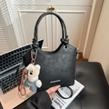 Black bucket shoulder bag with knotted handle, plush bear charm, and white brand logo - Black
