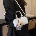 Sac cylindrique blanc avec bandoulière réglable et breloque ourson porté par un mannequin - Avec Pendentif / Blanc Cassé