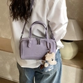 Sac Boston violet en faux daim avec breloque ours porté en bandoulière par un mannequin - Avec Pendentif / Violet
