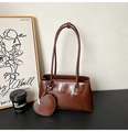 Detail of vintage brown oil wax leather tote bag with heart-shaped charm on wooden table - Brown