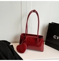 Detail of burgundy oil wax leather shoulder bag with a matching heart-shaped charm - Red
