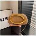 Close-up of khaki woven clutch featuring a large curved gold handle and fine metal chain - Khaki