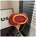 Close-up of red textured evening bag featuring a large gold C-shaped handle and chain - Red