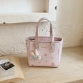 Light pink tote bag with cute animal prints and a plush bunny charm on stone table - Pink