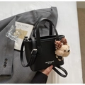 Detalle de bolso cubo de piel negra con colgante de oso y logotipo impreso - Con Colgante / Negro