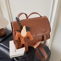 Brown leather crossbody bag featuring a designer orange pegasus charm and minimalist flap - Brown with Pendant