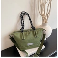 Close-up of green checkered handbag featuring black and white woven rope handles - Green