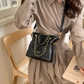 Schwarze gesteppte Beuteltasche mit Goldkette und Logo, von einem Model getragen - Schwarz