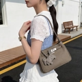 Taupe lychee leather shoulder bag with silver lock and horse charm on a female model - With Charm / Elephant Gray
