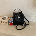Detail of black lychee grain leather bucket bag with metal cross lock and bear charm - Black with Pendant