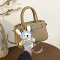 Minimalistische beige Leder-Beuteltasche mit Litschi-Struktur und süßem Plüschhasen - Khaki mit Anhänger