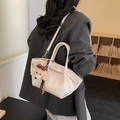 Bolso tote chic en cuero beige brillante con dije de perrito mostrado en una modelo - Con Colgante / Blanco