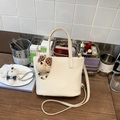 Close-up of beige lychee leather bucket bag with cute bear charm and adjustable strap - White with Pendant