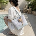 Borsa tote patchwork azzurra con ciondolo a orsetto mostrata in un ambiente soleggiato - Con Ciondolo / Blu