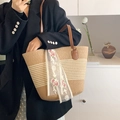 Beige Stroh-Tote-Bag mit floralem Spitzenband und braunen Ledergriffen am Modell - Khaki