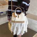 Borsa a secchiello bicolore beige e marrone con ciondolo a cavallo in un caffè - Con Ciondolo / Bianco Sporco