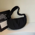 Detail of minimalist black nylon hobo bag featuring crescent shape and smooth zipper closure - Black