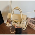 Detail of cream white pebbled leather handbag with gold hardware and a cute teddy bear charm - Cream White With Pendant