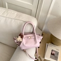 Detail of light pink bucket bag with plush dog charm on a cozy cream sofa - With Bear Charm / Pink