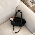 Detail of a black matte bucket bag with metal buckle and cute plush bear charm on a sofa - With Bear Charm / Black